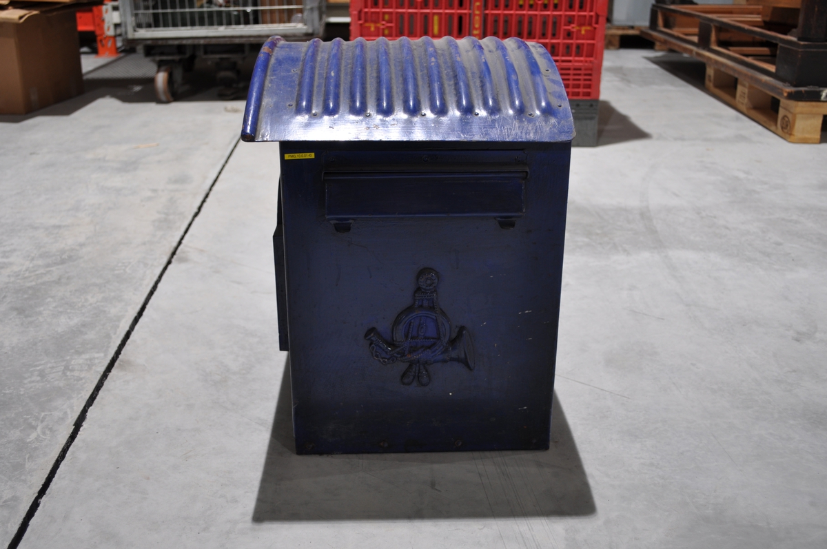 Blå tømmepostkasse i metall med tømmeplakat og brevinnkast på side.