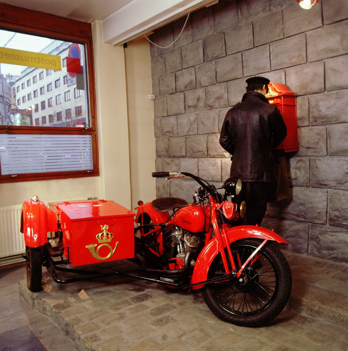postmuseet, utstilling, transport, motorsykkel, Harley Davidson med sidevogn og postlogo i gull, postbud i skinnjakke tømmer postkassen