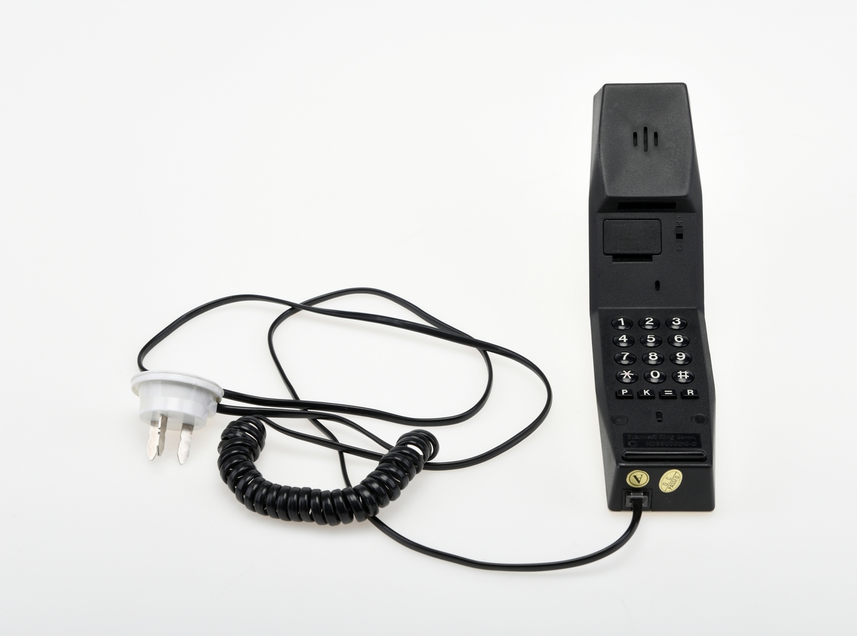 Hvit Ouno telefon fra Scanvest Ring Communications. Strømkabelen er av flat plast med hurtigkopling. Mangler tilhørende vegg/bordfeste.