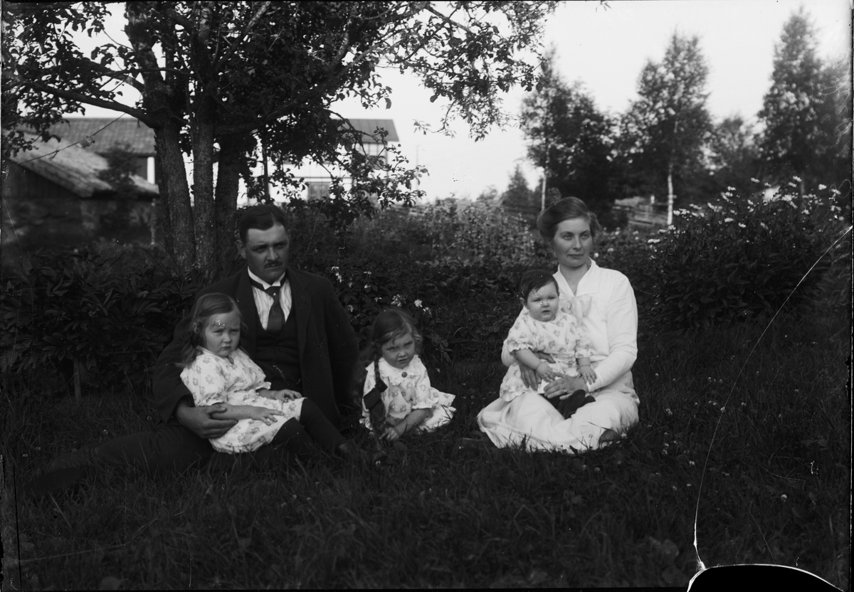 Familjen Mattsson sitter på gräsmatta, Gammelbyn, Uppland