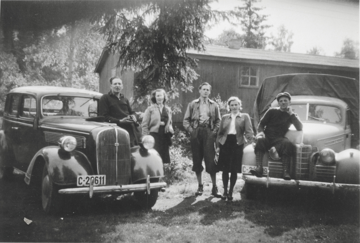 En gruppe unge mennesker er samlet ved biler. Fra venstre: Opel Super Six 1937-38, Oldsmobile 1939 ombygd til pickup.