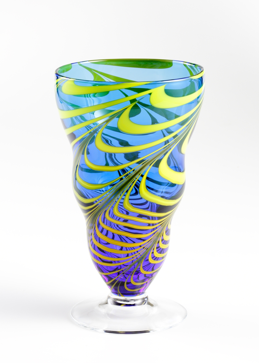 Formgiven av Erika Lagerbielke. Vasi blått glas (degelfärgat glas) med kammad dekor i gult. Ofärgad fot. Serien slopades 1995.