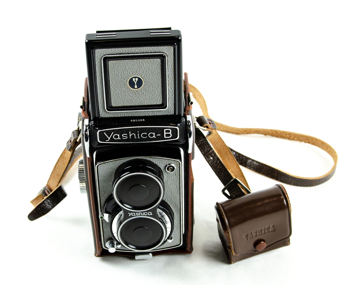 Kamera Yashica, modell B. Monterad i en tillhörande beredskapsväska där alla betjäningsdelar är synliga och lättillgängliga. Väskan är i läderutförande. Förvarad i originalkartong. Tillverkad av Yashima Optical Ind. Co., Ltd., Tokyo, Japan.