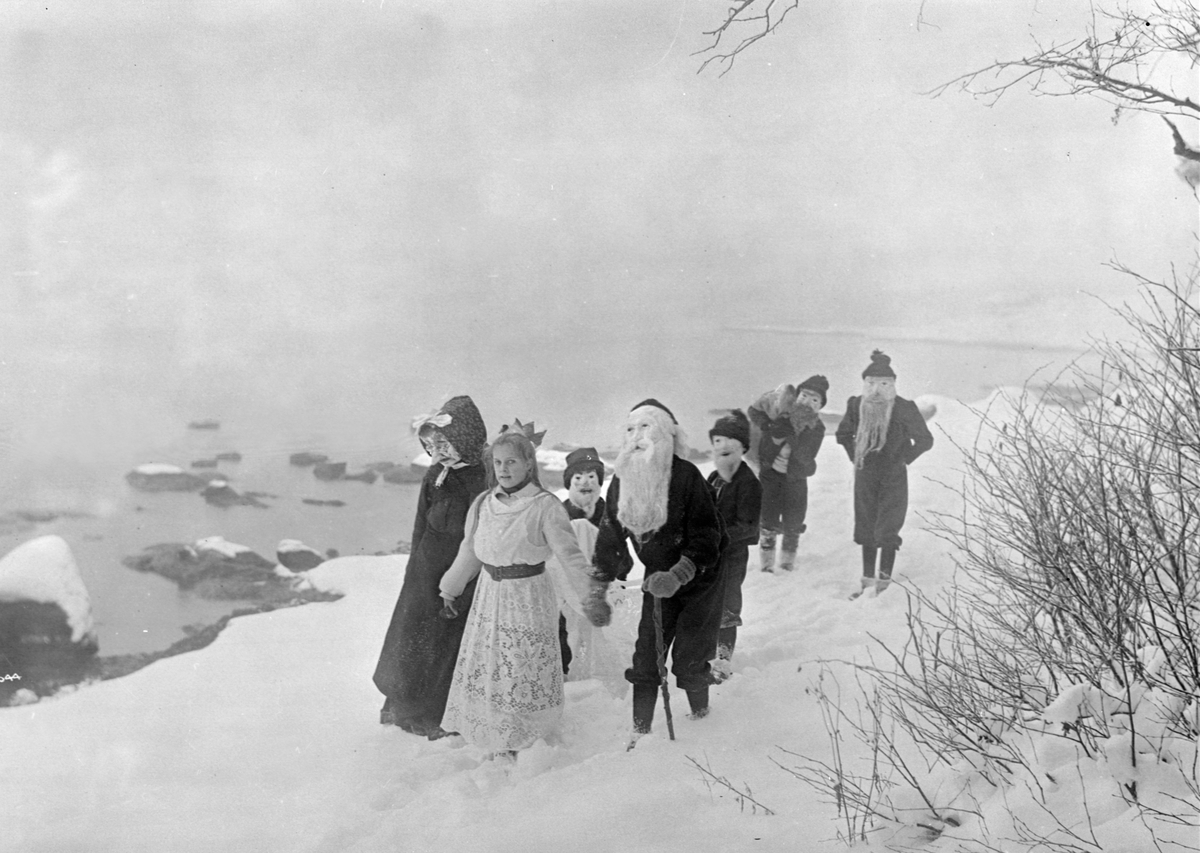 Barn spiller skuespillet Maias drøm ute i skogen. Her går følget langs stranden. Fotografert vinteren 1907.