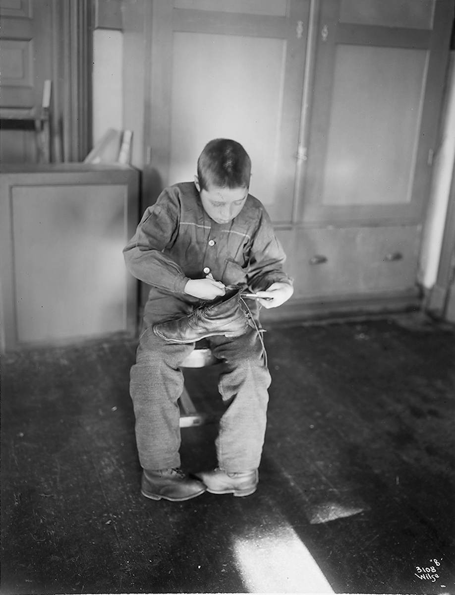 Funksjonshemmet gutt reparerer skotøy.