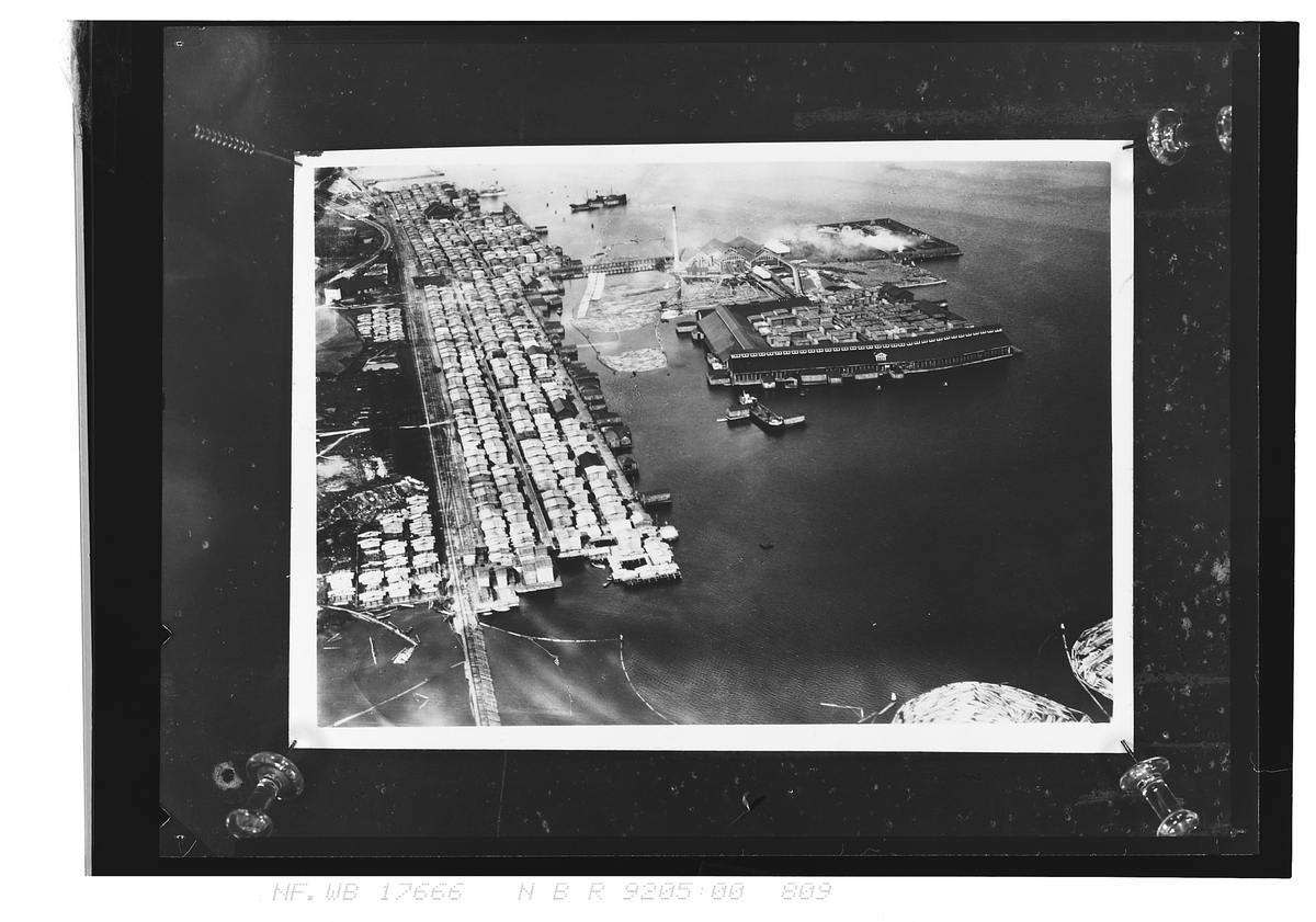 Stort industriområde. Tømmer ligger i sjøen, trelast under tak, lasetbåter ligger i sjøen, Admiral Sparre. Fotografert 1924.