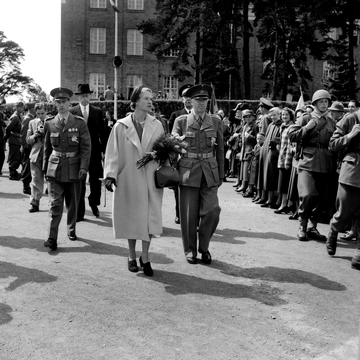 Prinsessan Sibylla med militära dignitärer och beväringar passera över kaserngården till T 1 i Linköping. Hennes besök var föranlett av 1953 års försvarsutställning som var förlagd till staden.