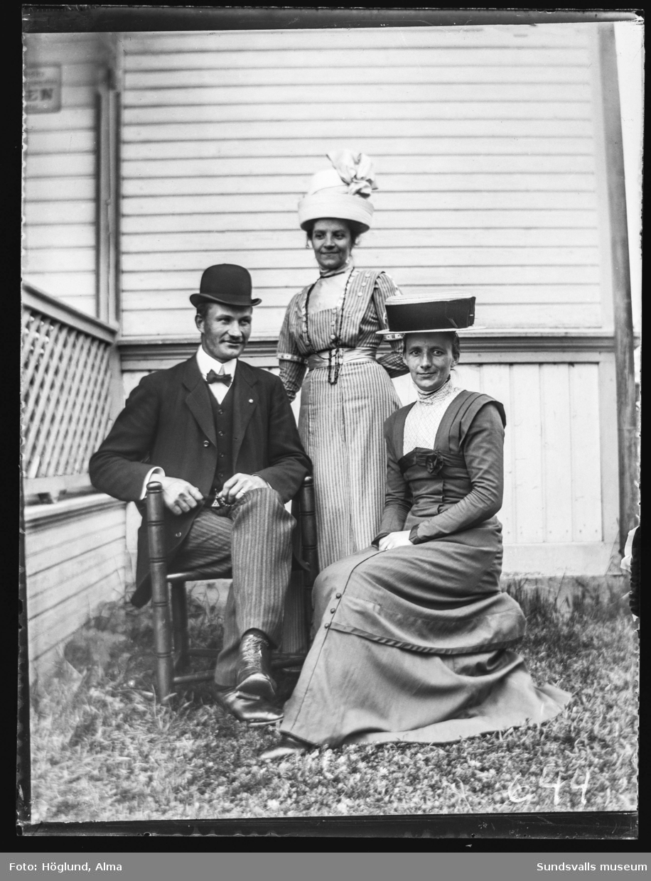 Emil och Sanna Eriksson samt i mitten en oidentifierad kvinna. De båda kvinnorna bär extravaganta hattar.