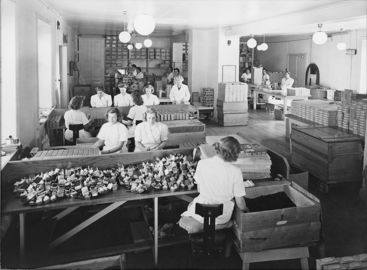 Interiör från Ahlgrens Tekniska Fabrik under 1940-talet på Brynäs, Gävle. Personalen handpackar Läkeroltabletter i plåtaskar.