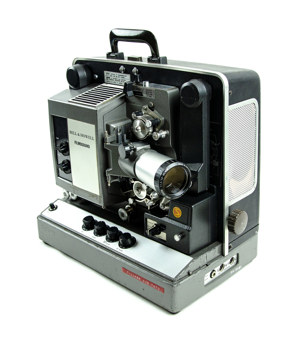 Ljudfilmsprojektor, Bell & Howell filmsound. Model 643 SK. Till projektorn hör även en anslutningskabel, två tomma filmrullar samt sex stycken Atlas projektorlampor. Detta är förvarat i en specialanpassad låda av plast. Den gråa lådan är förstärkt i alla hörn med svarta metallhöljen.