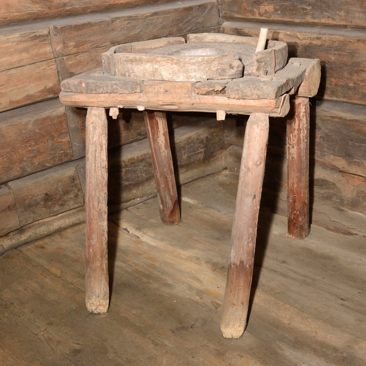 Handkvarn tillverkat i trä och sten. Kvarnen utgörs av rund sten med runt hål mitt i, samt med ett draghandtag i trä. Stenen är placerad i en rund ram ovanpå en fyrbent fotställning. Fotställningen med enkla, lätt snedställda ben. Ram och fotställning av trä.