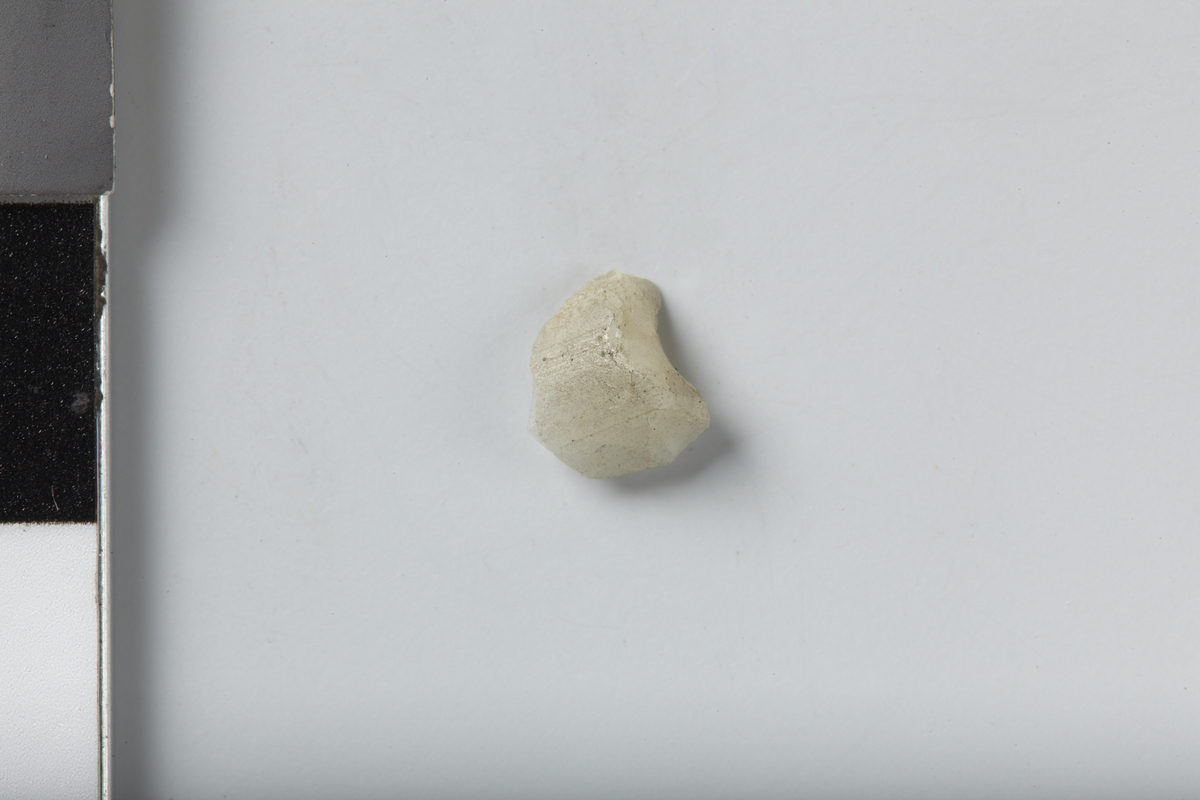 Fragment av hvit, glassperle med spor etter gjennomgående hull. Stl: 1,15 cm og stb: 1 cm. Vekt: 0,05 g.