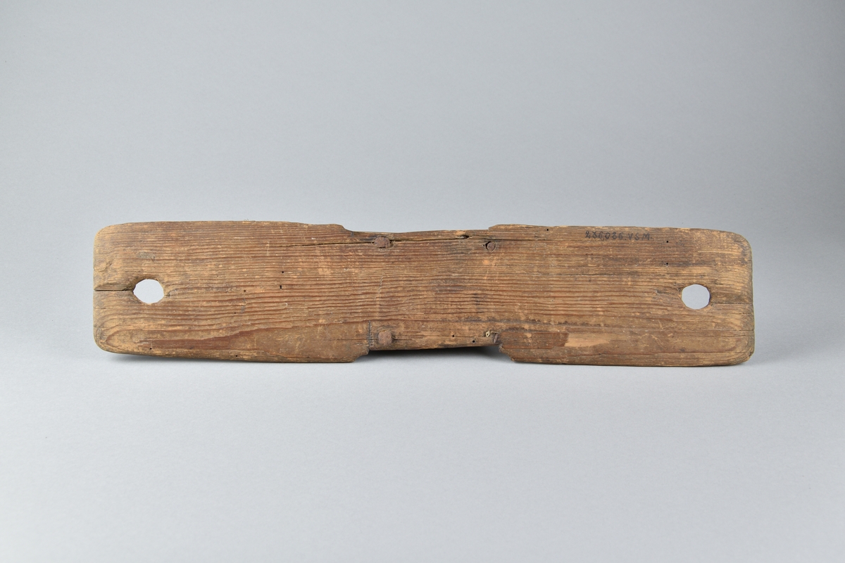 Häckla tillverkad av trä och järn. Underst ett platt och fyrsidigt bräde, med ett runt hål vid båda kortsidorna. I mitten av brädet en upphöjd avsatts, besatt med järntaggar. Häcklans ena sida med inskriften "KLD 1781". 
