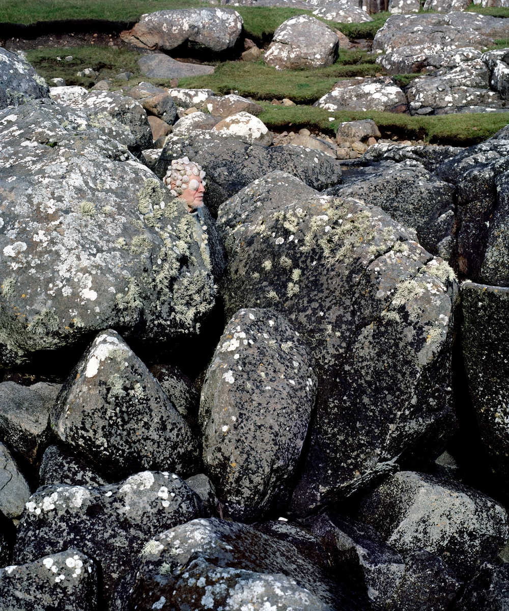 Portrett av Niels, som går i ett med et landskap av steiner på Færøyene. Bildet er en del av serien "Eyes as Big as Plates".