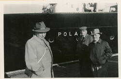 Tre menn på havna i Vardø. Til havn ligger MS Polarlys