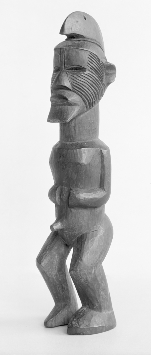 Skulptur (Gudebilde)
Gudebillede af træ, paa hovedet en sortmalet hjelm, ansigtet tatoveret.
Tre