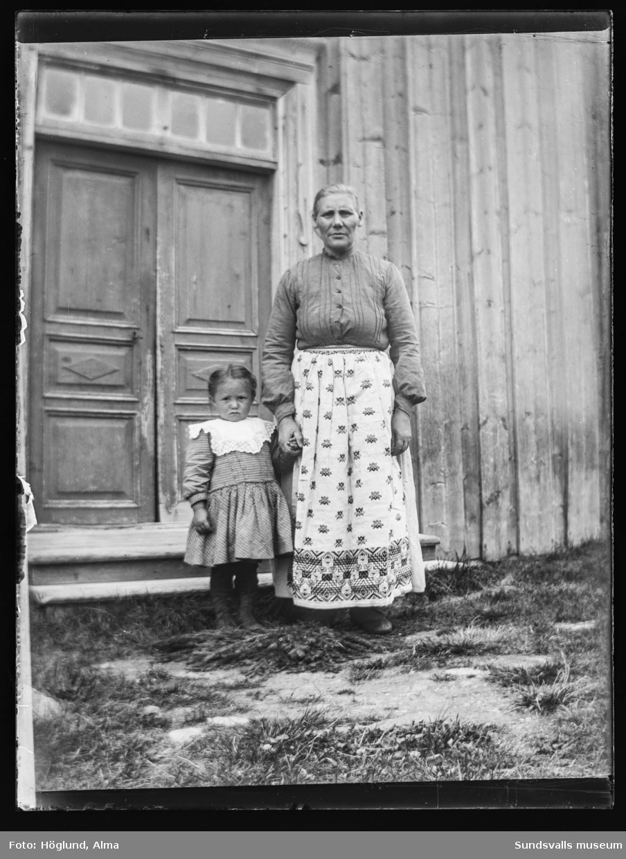 En äldre kvinna och en liten flicka på trappen till ett trähus med vackra dubbeldörrar. Två bilder.