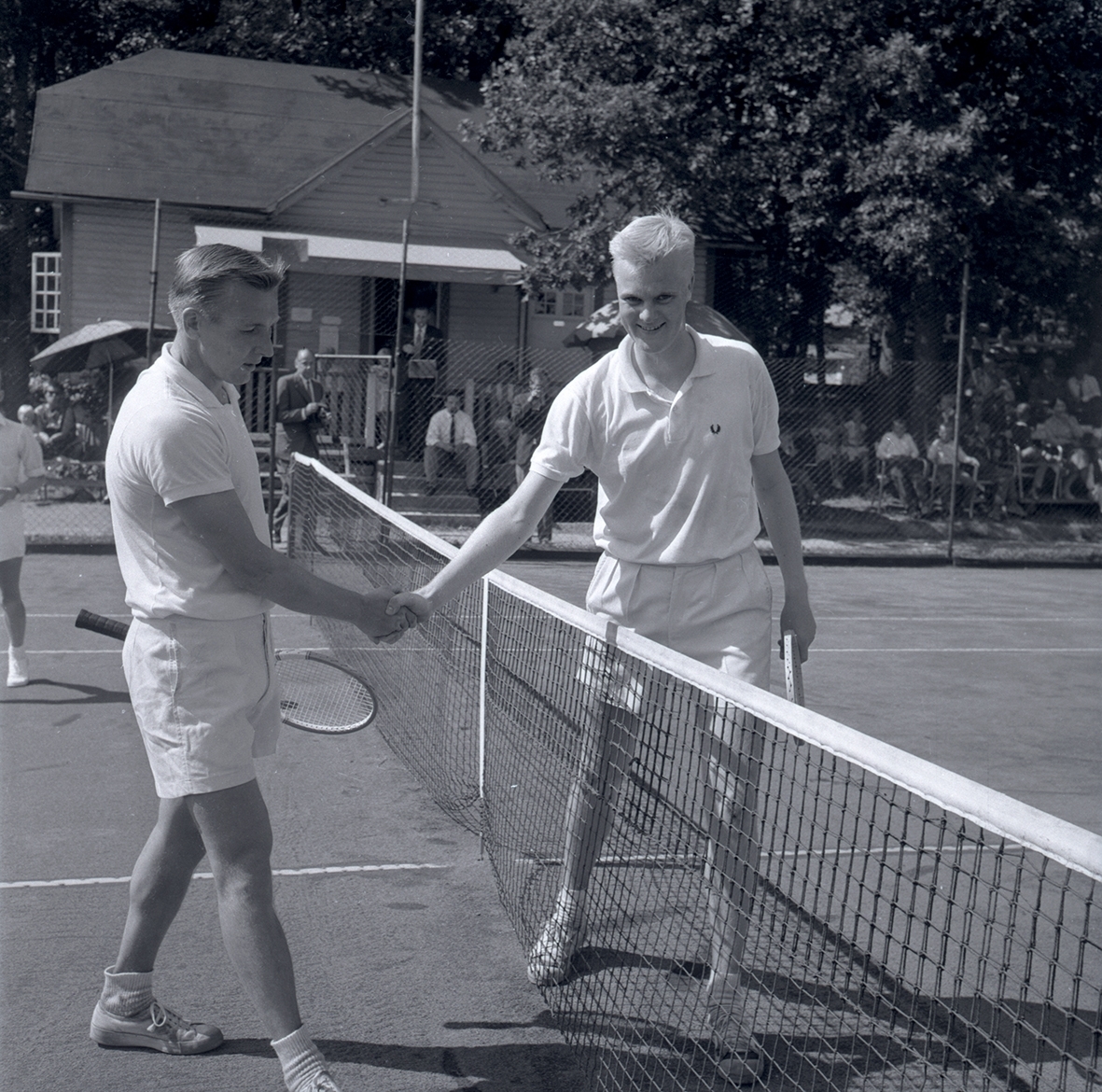 Fyra personer vid tennisbanan 1958. Skakar hand. Namn som medföljde bild: J E Lundkvist (t.h.) och Bengt Axelsson.