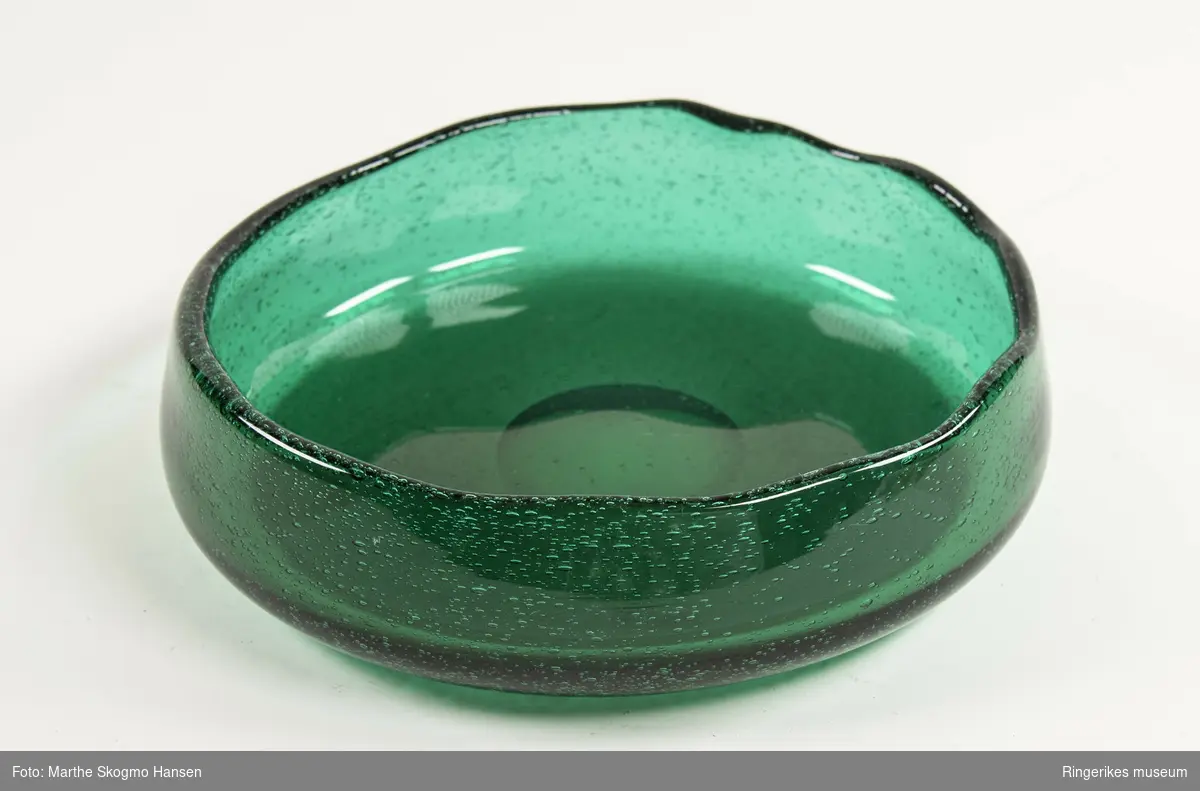 Grønn rund håndblåst glassbolle med ujevn kant. Fra serien Grønland designet av Arne Jon Jutrem for Hadeland Glassverk i 1953.