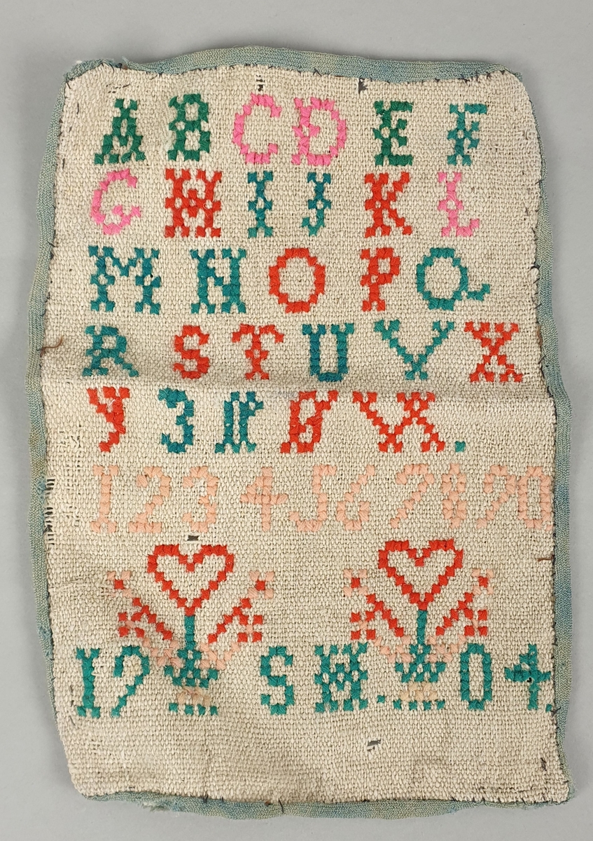 Broderte bokstaver, tall, årstall og initialer på strie.