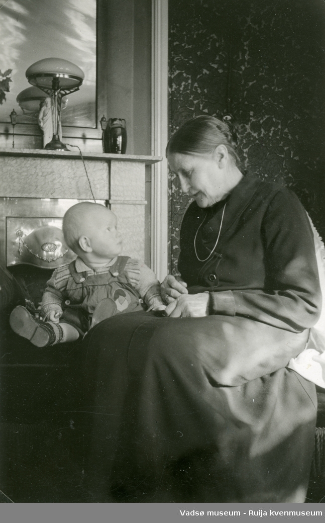 Fru Simonsen med Erling Jan foran kaminen i Olsens stue i Vadsø. ca 1940-1945.
