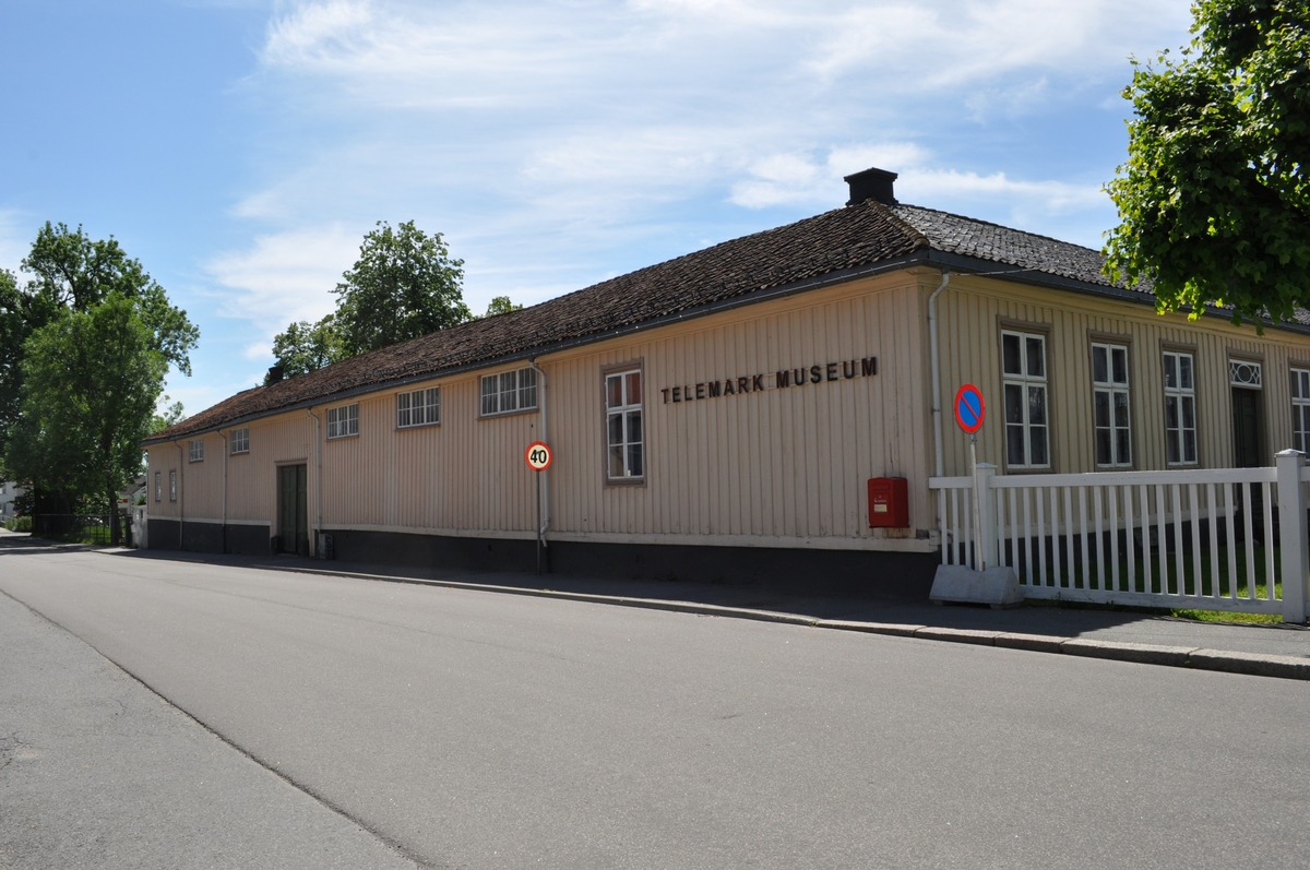 Østre uthusfløy på Søndre Brekke gård. Tømret og panelt uthusfløy som opprinnelig inneholdt vedskjul, kjøreport og vognskjul. Oppført samtidig med de øvrige fløyene 1811-13. Vaktmesterleilighet innredet 1970-75.