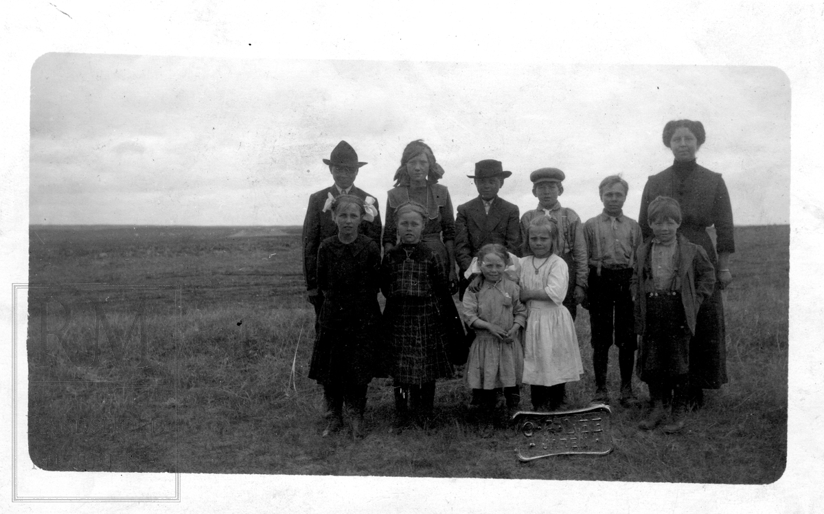 En familie står oppstilt med prærien i bakgrunnen.