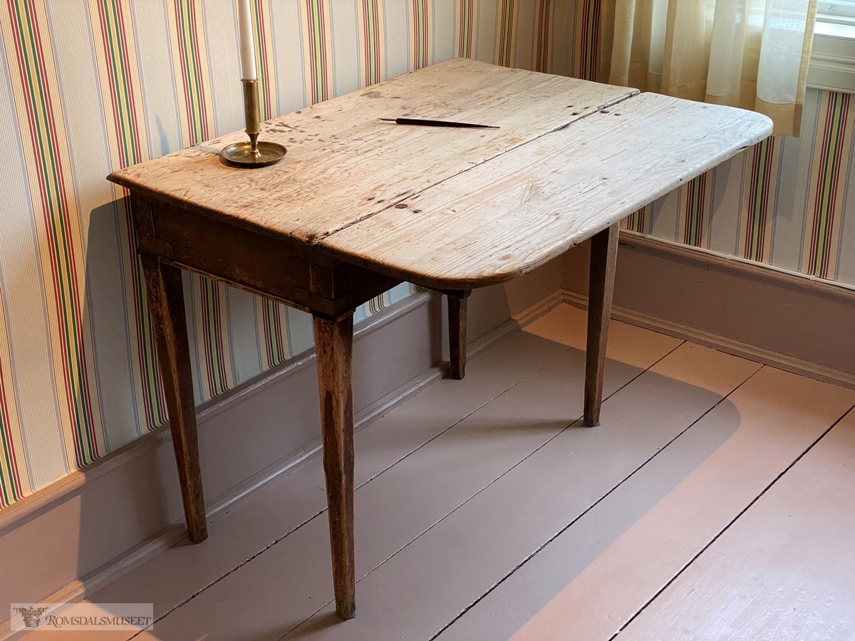 Trebord med avrundet bordplate, og en liten klaff med hengsler og en utskyvbar fot. Bordet har sarg og en skuffe med knott.