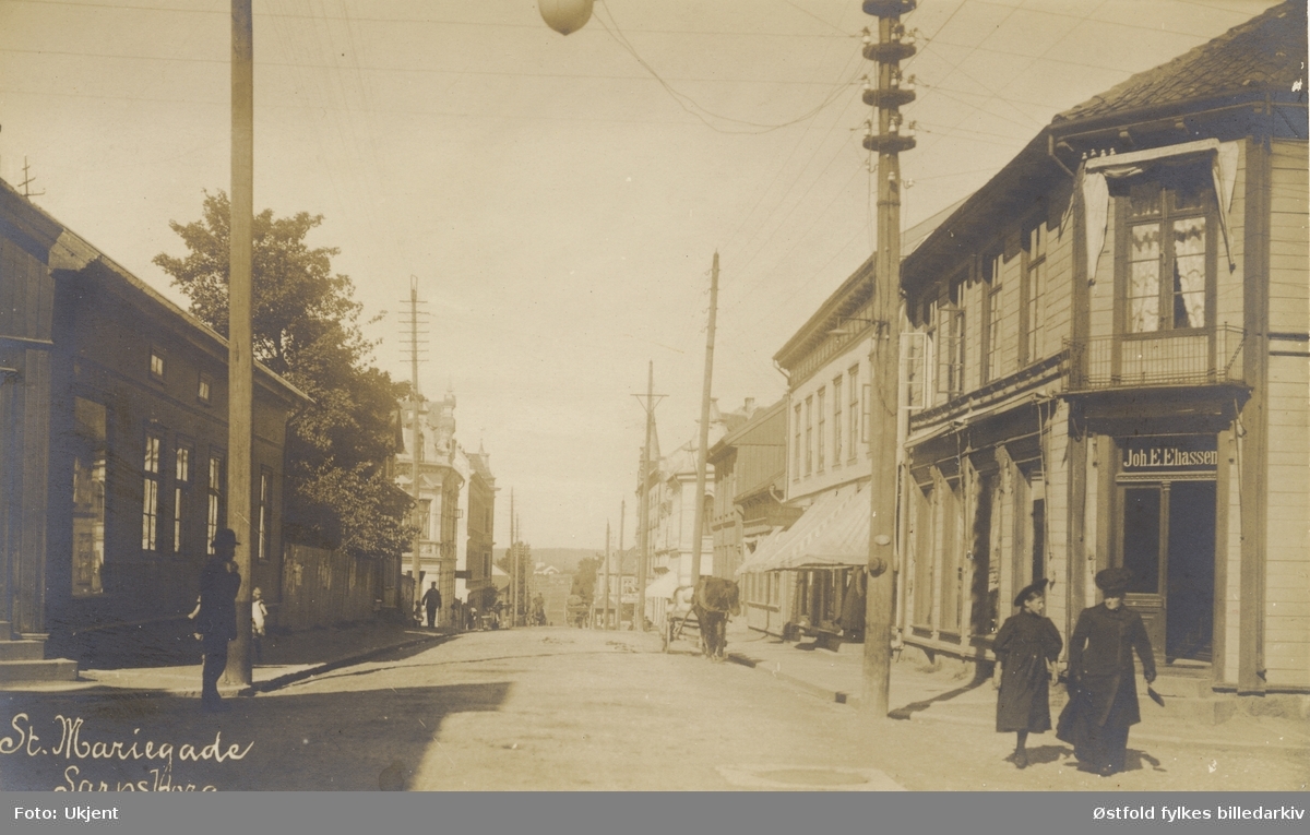 Gateparti fra St. Marie gate i Sarpsborg 1906. Postkort. Forretningen til Joh. E. Eliassen på høyre side.