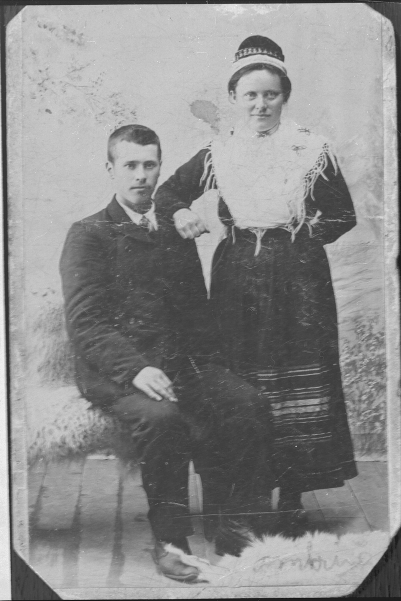 Studioportrett av en kvinne i samiske klær og en mann, sannsynligvis et brudebilde.