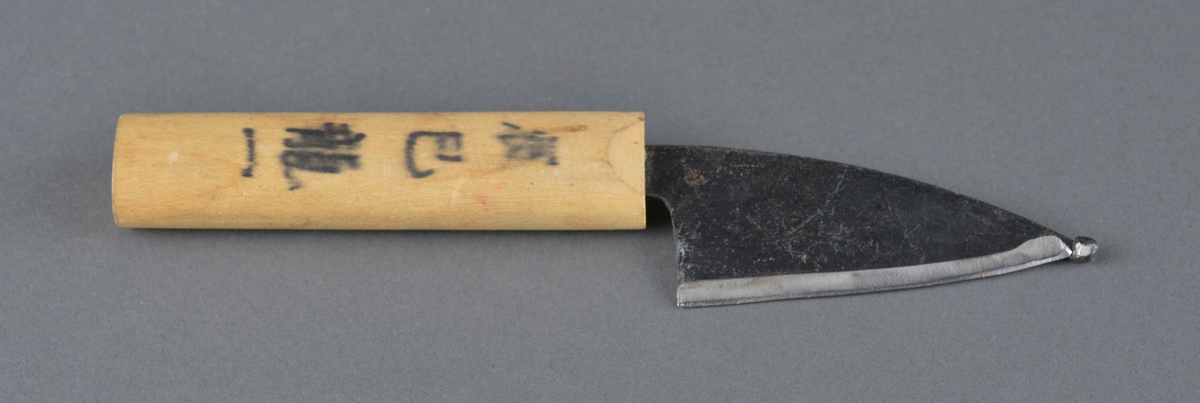 Kniv med trehåndtak og kort, bredt knivblad med en kule på knivbladets spiss. Ikke kjent om kula er original eller om den er sveisa på i ettertid. Skaft i lyst trevirke med asiatiske skrifttegn på langs.