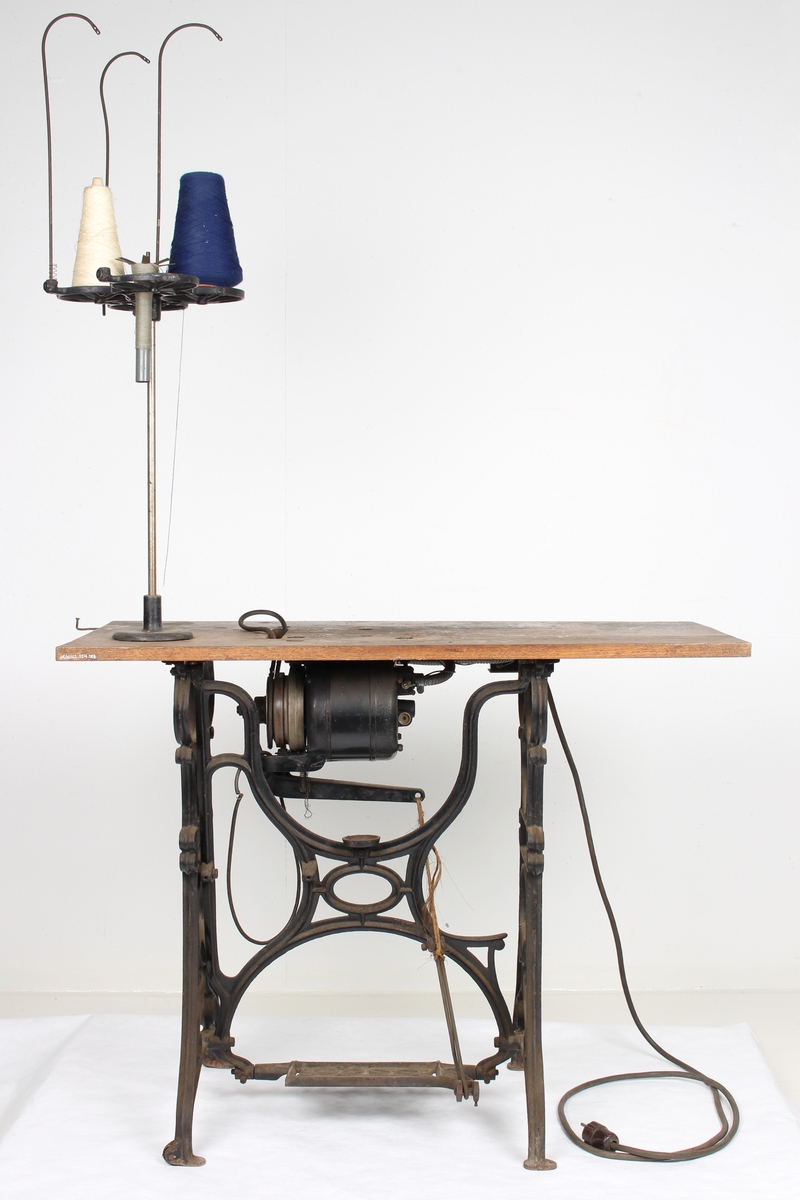 Symaskinbord med trømaskin og elektrisk motor.
