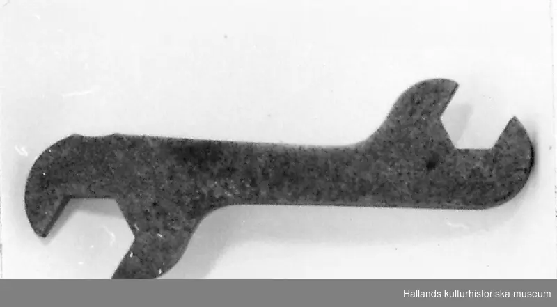 Dubbelnyckel (Skruvnyckel, U-nyckel), något vinklat skaft, av stål. Längd 14 cm. Bredd 4,2 cm. 