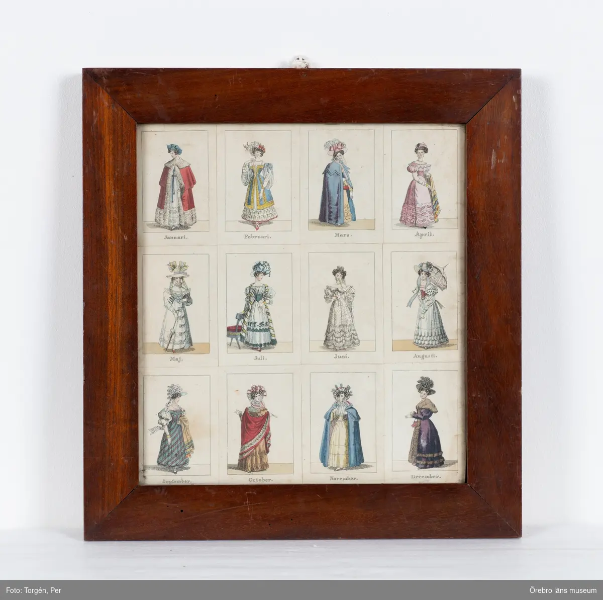 Tavla med 12 kolorerade dräktbilder framställande månaderna inom glas och polerad träram.