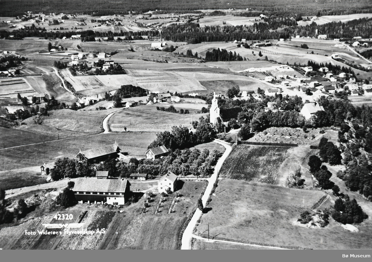 Flyfoto av Bøhaugen med kyrkjene og Midt-Bø gardane, tatt 5. juli 1952.