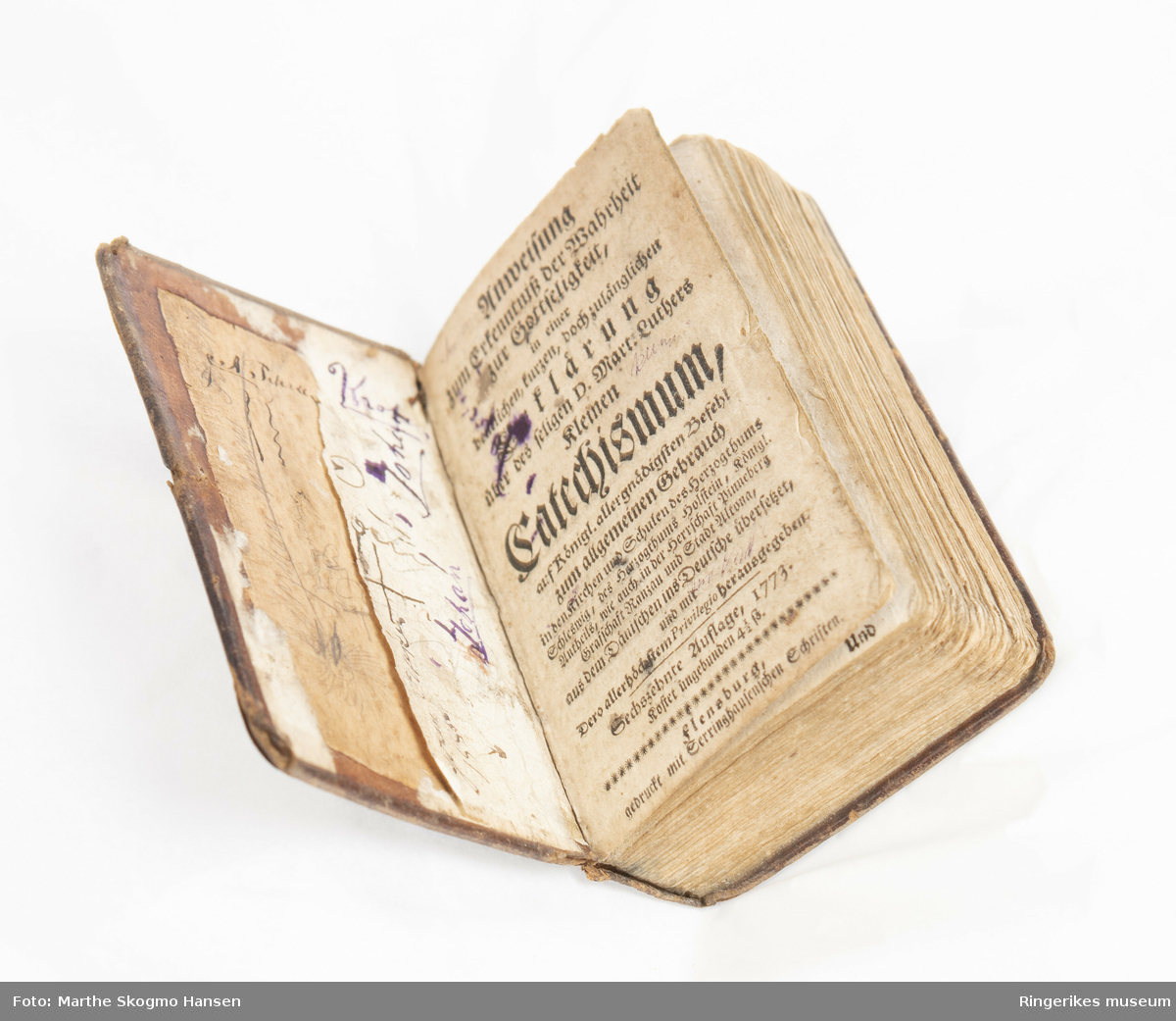 Catechismum. Liten tysk bok med skinnpermer. Martin Luthers lille katekisme. 16 opplag trykket i Flensberg i 1773. Uleselig håndskrift på innsiden av begge permer. Lite trekanta bokmerke inni boka med motiv av ku i gull på rød bakgrunn.