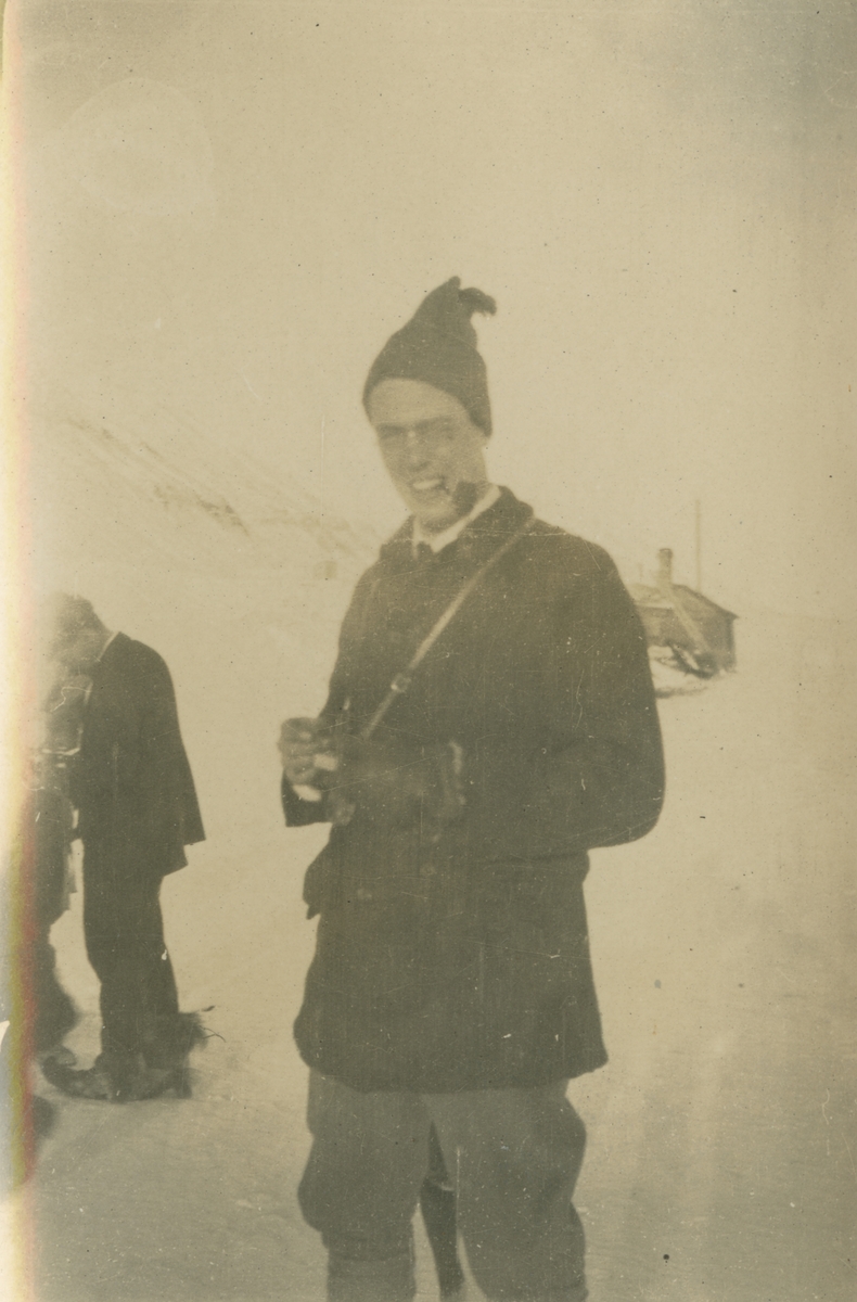 Fotografi från expedition till Spetsbergen. Motiv av man med toppluva och pipa som poserar i snön.