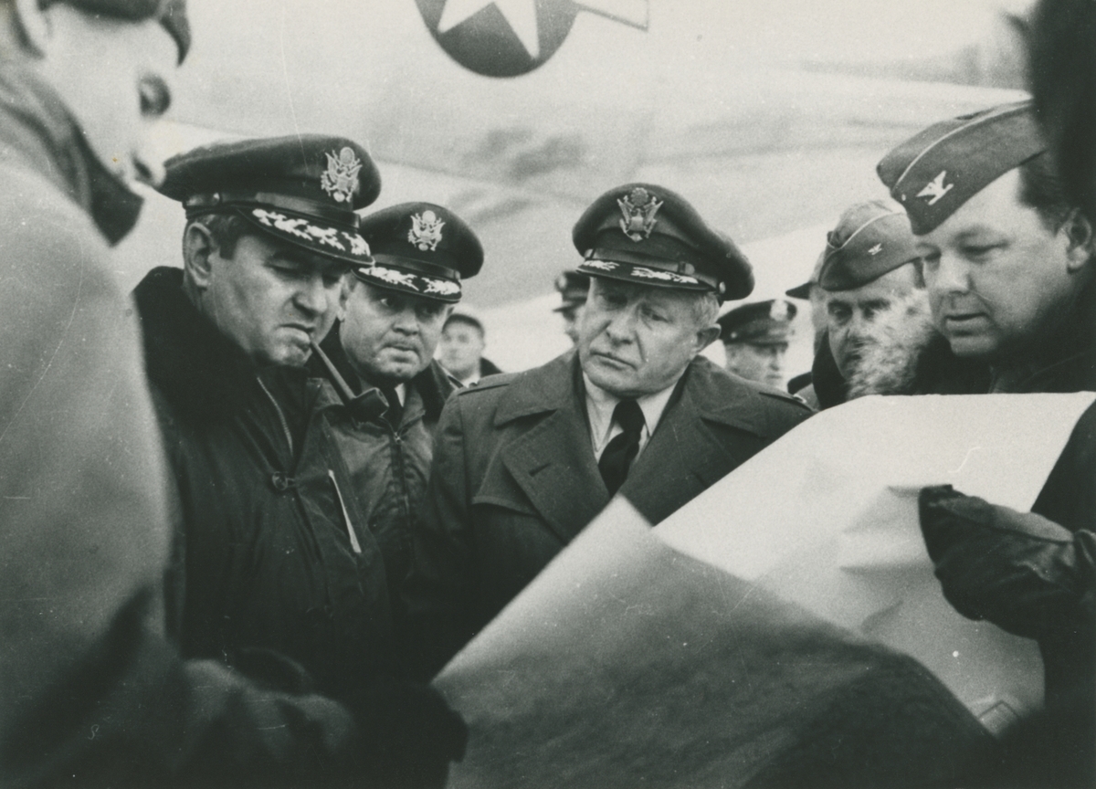 Fotografi från låda märkt Bernt Balchen. Balchen var norsk-amerikansk flygare, polarforskare och militär. Motiv av Bernt Balchen och flera andra militärer. Möjligtvis tagen på Thule Airbase på Grönland 1949. Mannen i mitten av bilden är Bernt Balchen.