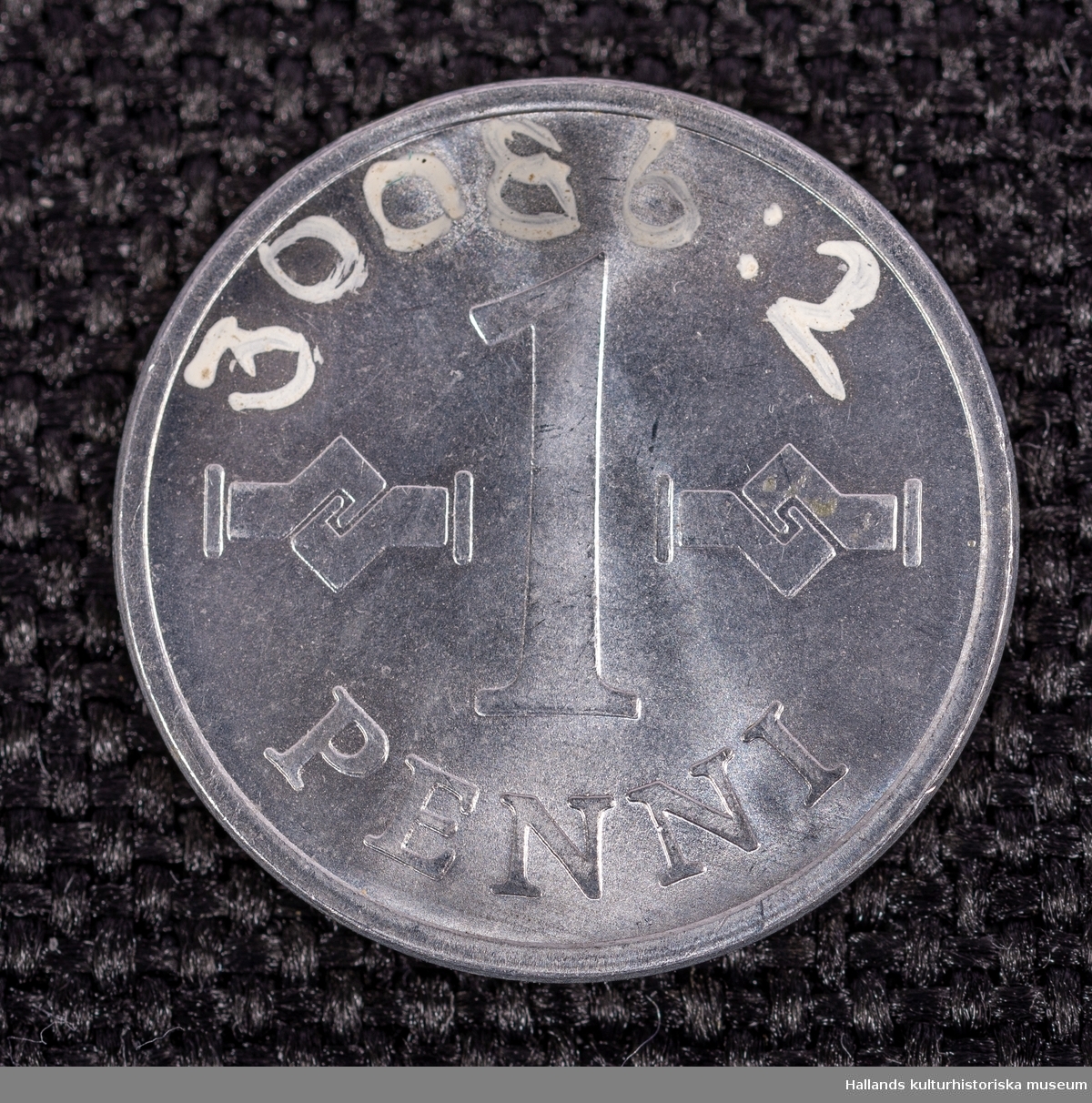 Två finska mynt av vitmetall (delar 1 och 2). Präglingsår 1969 respektive 1970. 1 penni.Diameter 10 mm. Åtsida: Präglingsår, dubbel swastika samt texten "SUOMEN TASAVALTA" (Republiken Finland). Frånsida: Valör. 