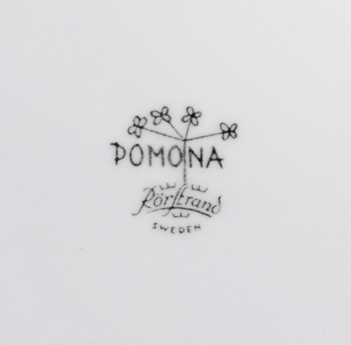 Tallrik av vitt porslin. Mönster: "Pomona" stiliserade grönsaker och örtkvistar. Design: Marianne Westman. Stämplad: "Pomona, Rörstrand, Sweden". Tillverkades 1956 - 1971.