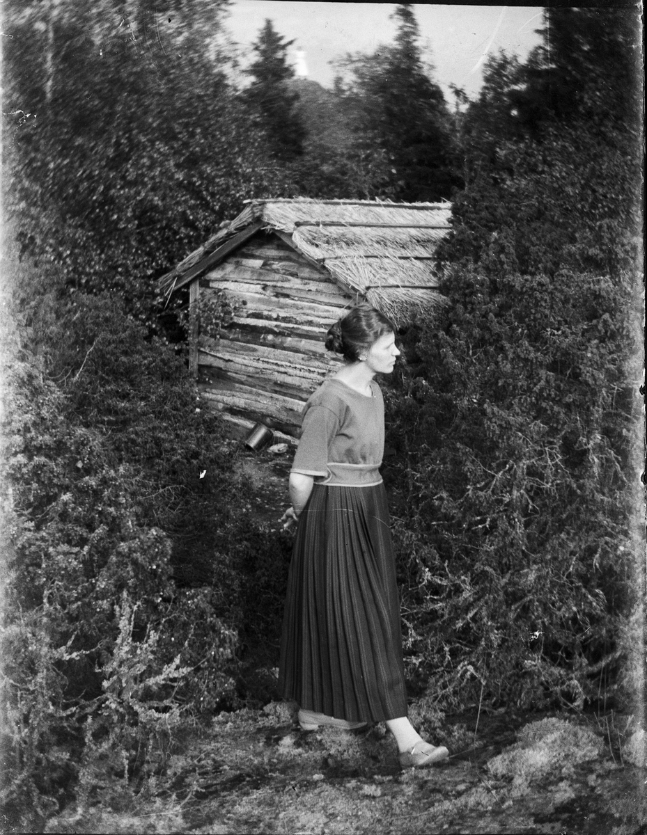 Kvinna vid timmerstuga, Karlskoga, Värmland