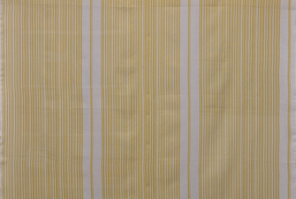 Rayonulltyg, 1960-tal.
"Grafit", design Lisa Gustavsson
Gardintyg på originalbredd 120 cm. Tryckt mönster med gula ränder på vit botten. 
Tvinnat garn i varp och väft.
Rapport - x 40 cm