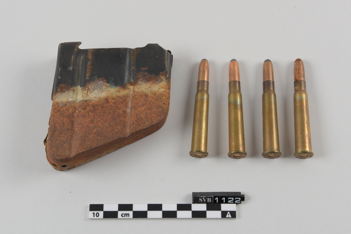 Metallbeholder med 4 skudd med blyspiss. Magasinet er delvis rustet. Patronene er med kant nede.
