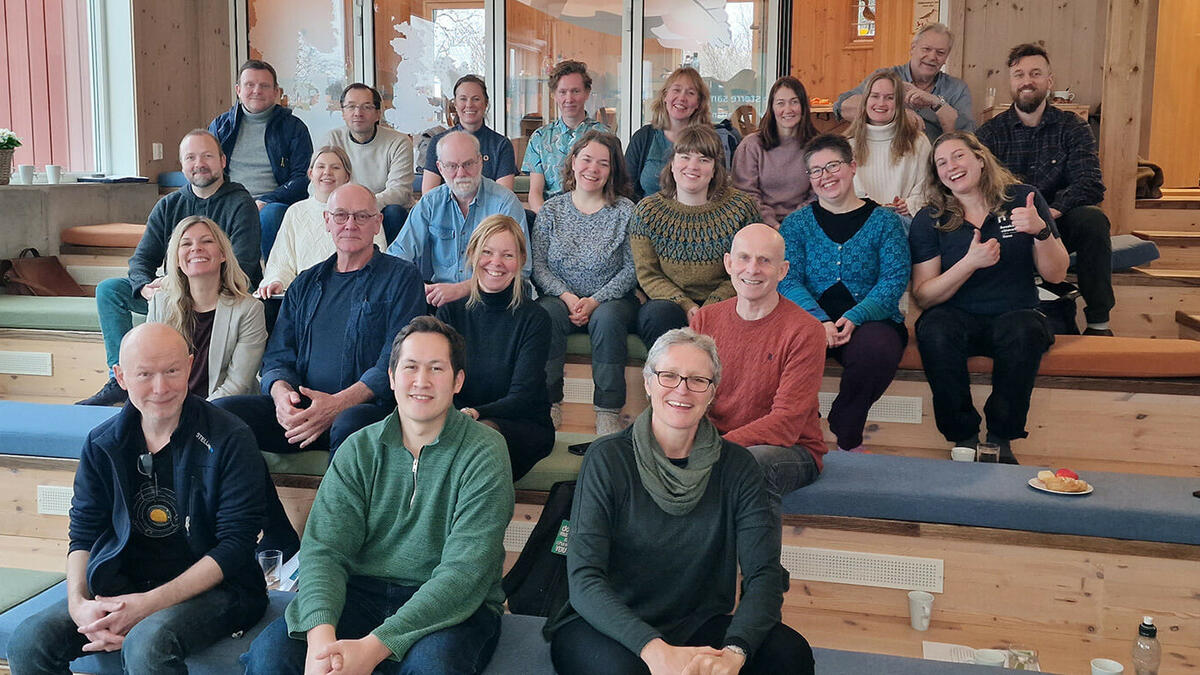 Foto av en gruppe mennesker som sitter i et auditorium og smiler mot kamera