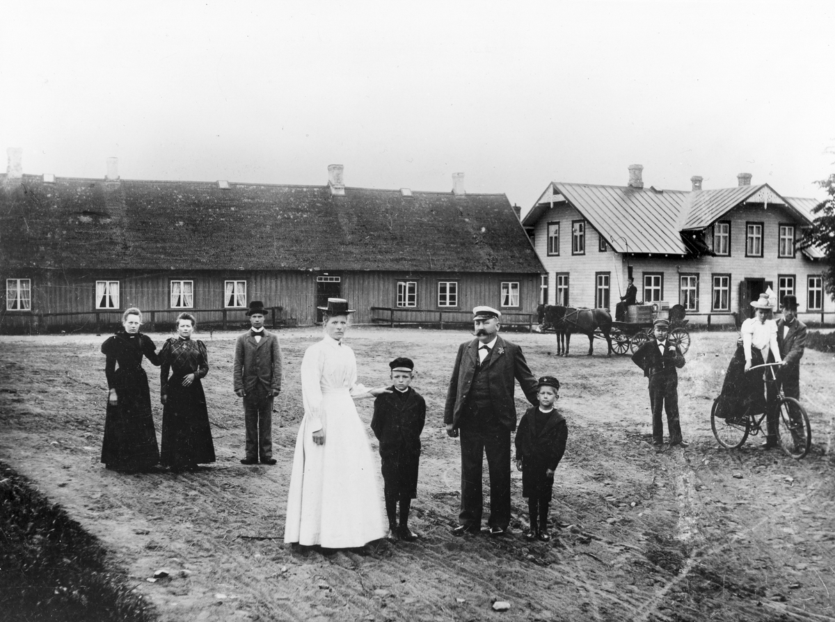 Folk i finkläder utanför en herrgård, med en hästvagn i bakgrunden i Kvibille socken.