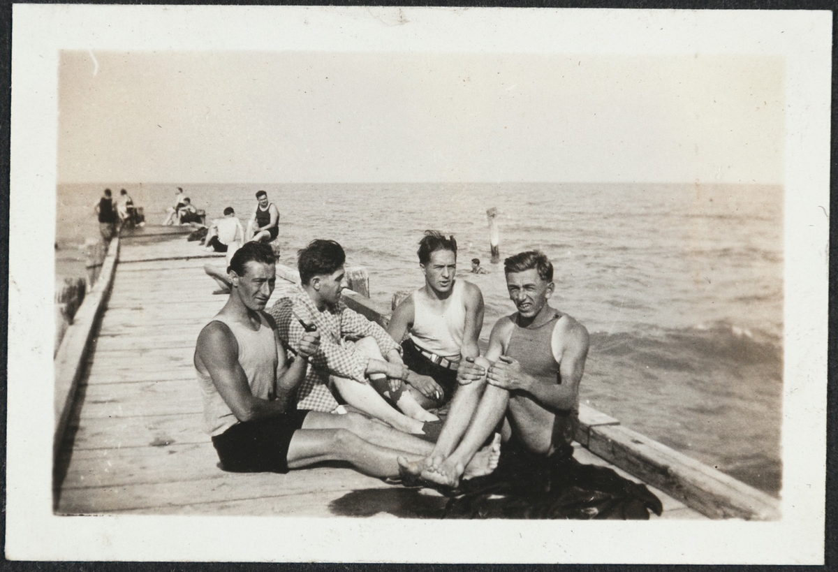 Fire menn sittende på en pir i badetøy. Havet sees i bakgrunnen. Bjarne Fixdal sitter til venstre og Kalle (Karl Bårdsen) til høyre.