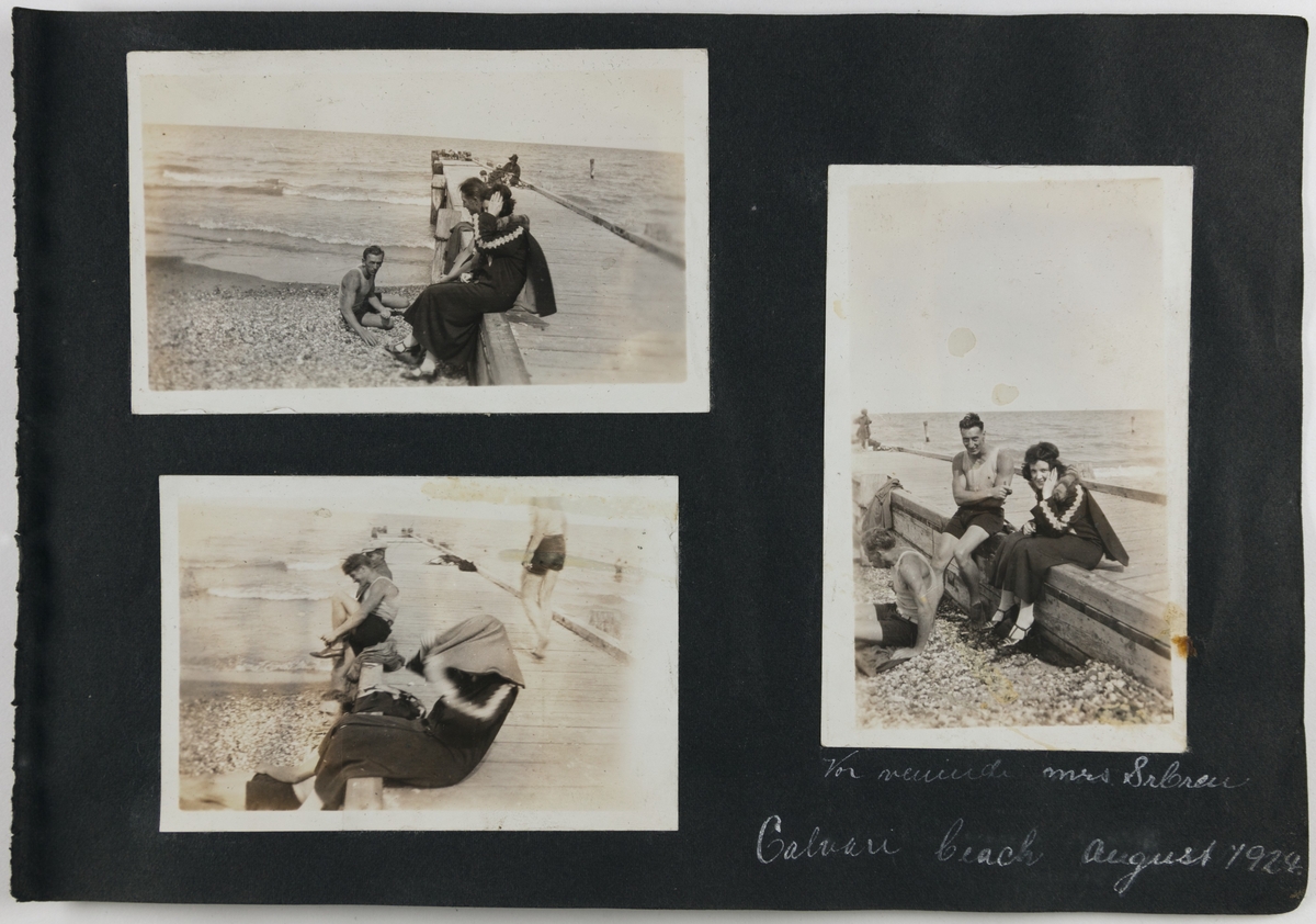 To menn og en kvinne på stranden, Calvary beach, 1924. Pir eller kai i forgrunnen og flere i bakgrunnen Man skimter mange mennesker på stranden og badende i havet. Kvinnen tørker håret under en håndduk.