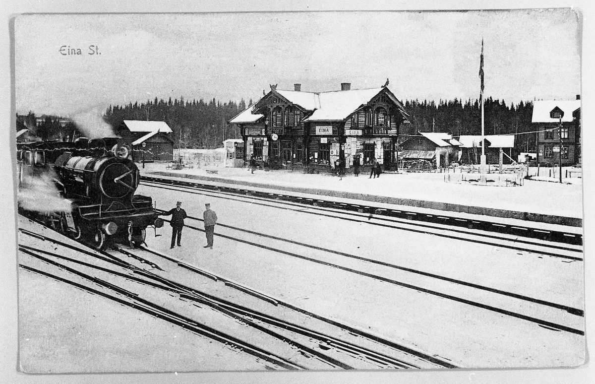 Eina stasjon. Postkort. Bildet er tatt foran Eina stasjon. I bakgrunnen Fjordheim Hotell. Mannen til høgre foran lokomotivet er Olaf Nordsveen.
