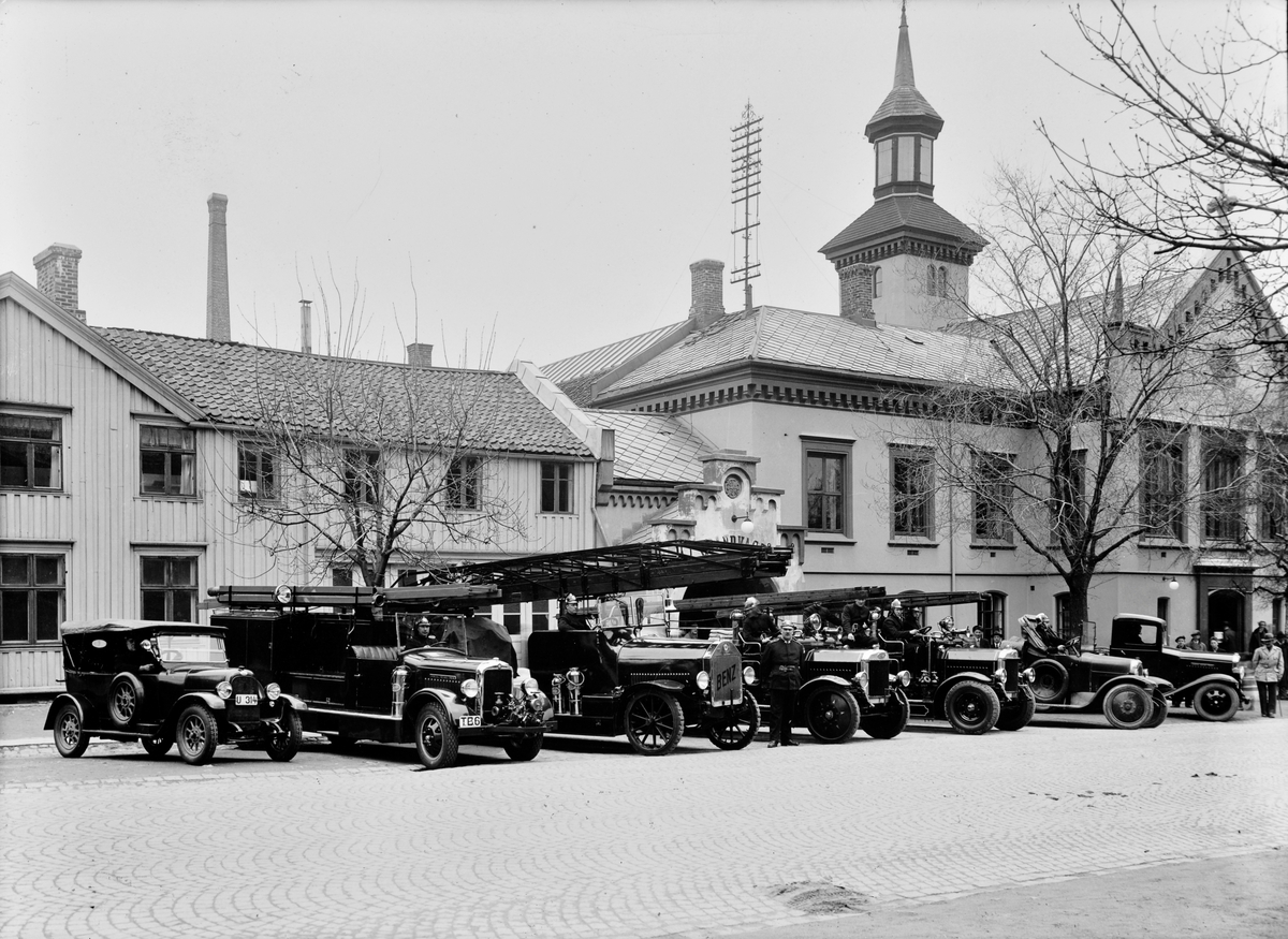 Oppstilling av brannbiler og brannmenn foran brannstasjonen og det tidligere rådhuset
