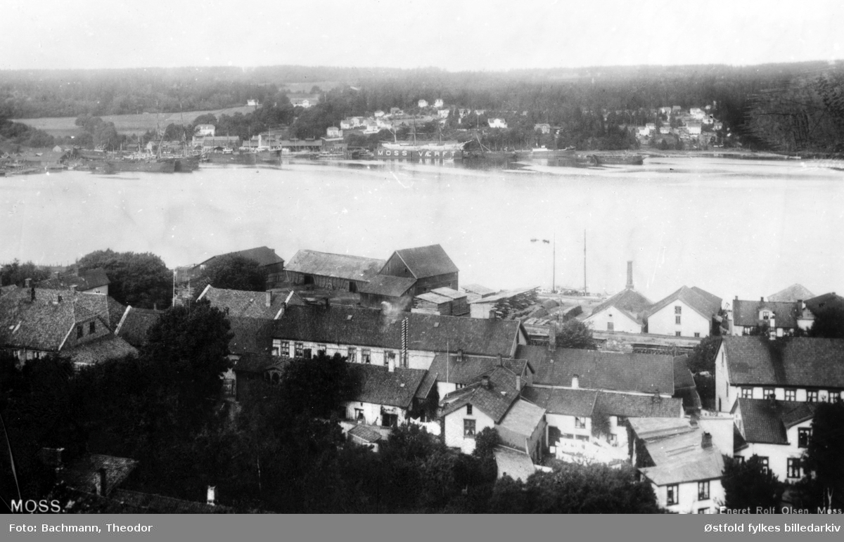 Oversiktsbilde fra  Moss ca. 1910,  sett fra kirkespiret mot nord-vest og Mossesundet med Jeløy i bakgrunnen. Stort hus i midten er Maxegården i Storgata 24, 1/2 hus til høyre er Hafnergården, Storgata 26. Byggene bak er Vogt og Holst.